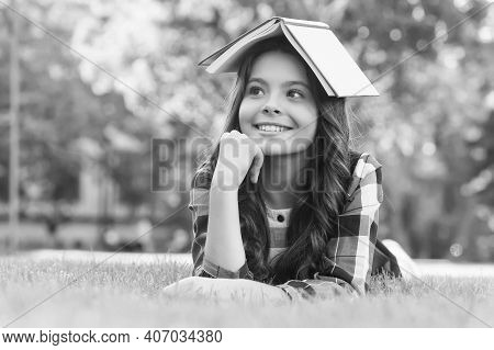 This Is My Reading House. Happy Child Hold Book On Head Lying On Green Grass. Lending Library. Readi