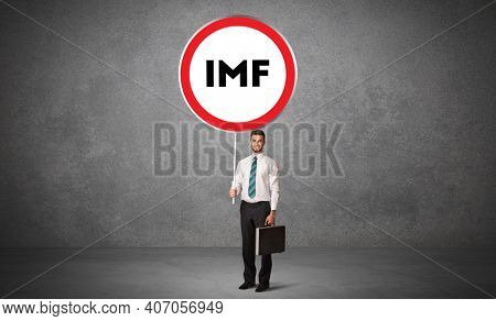 Young business person holdig traffic sign with IMF abbreviation, technology solution concept