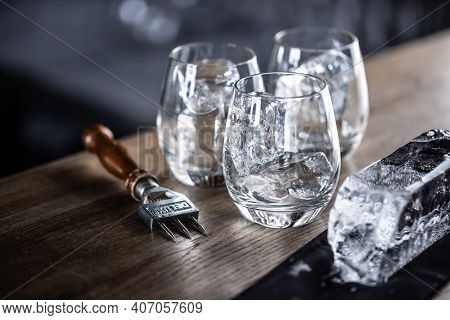 Glasses Cooled For Cocktails With Ice With A Big Ice Cube And Ice Chopper Aside.