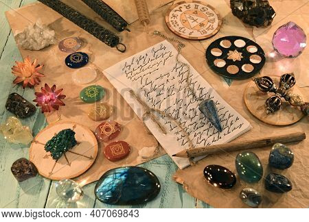 Crystal Stones With Chakras, Candles, Ritual Objects And Paper With Lettering And Text On The Table.