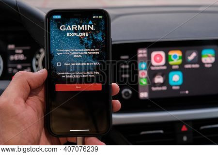 Garmin Explore Logo On The Screen Of Smart Phone In Mans Hand On The Background Of Car Dashboard Scr
