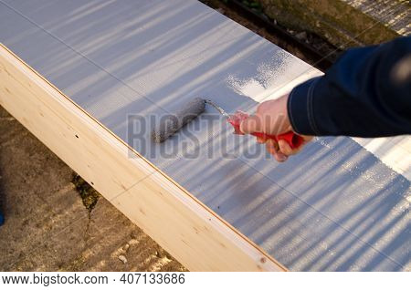 Close Up Of Painter Arm Painting A Wall With Paint Roller, Wood Wardrope Is Painted By Grey Color Pa