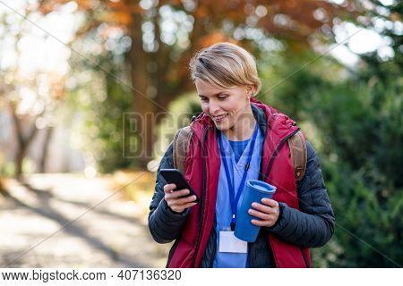 Woman Caregiver, Nurse Or Healthcare Worker Outdoors On The Way To Work, Using Smartphone.