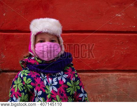 Young Girl In Warm Clothes Protective Face Mask On Terracotta Red Wall Background. Urban Style Stree
