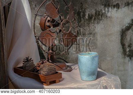 Old Vintage Brown Metal Fan And Dried Cerbera Oddloam's With Blue Ceramic Mug Handmade On Pink Table