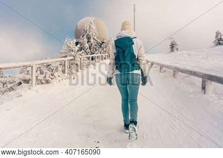 Winter hike at the peak of the Grosser Arber mountain with woman walking up a path