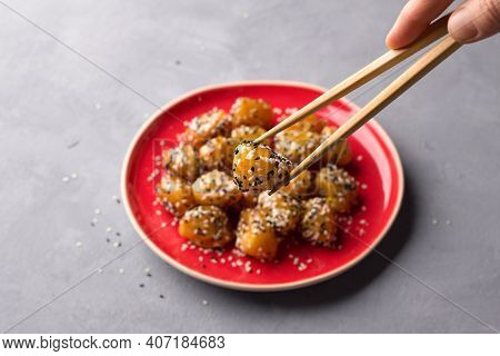 Traditional сhinese Fried Apples In Caramel With Sesame Seeds On Red Vintage Plate With Chopsticks O