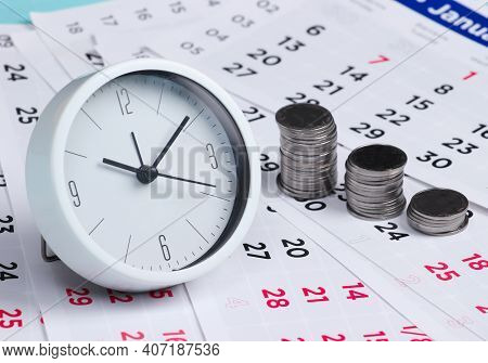 Clock With A Stack Of Coins On A Monthly Calendar. Time Is Money. Time To Invest