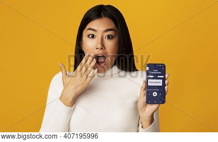 Surprised Asian Woman Holding Smartphone With Opened Voice Translation App On Screen, Using Online T