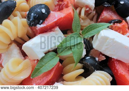 Close-up Of Itlian Fusilli Pasta Salad With Olives, Tomato, And  Feta Cheese In Blue Bowl On White T