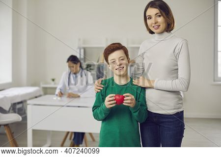 Smiling Boy And His Mother Standing With Red Heart After Visiting Woman Doctor Pediatrician