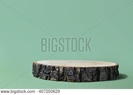 Podium For Product Presentation. A Minimalistic Scene Of A Felled Tree Lies Against A Green Backgrou