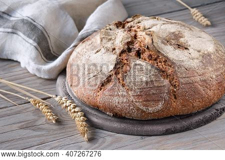 No Knead Handmade Loaf On Cutting Board On Wood With Linen Towel, Spelt Ears. German Bauernbrot Mean