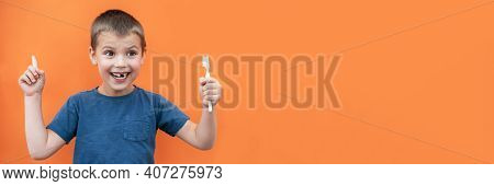 Boy Without Milk Upper Tooth In Blue T-shirt Holds Toothbrush In Hand On The Orange Background. Copy