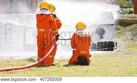 Firefighter Fighting With Flame Using Fire Hose Chemical Water Foam Spray Engine. Fireman Wear Hard