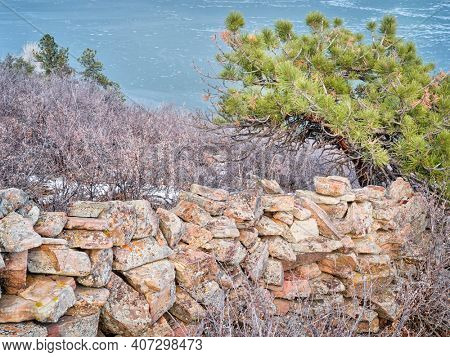 old stone fence at foothills of Rocky Mountains above Horsetooth Reservoir - a popular recreational area in northern Colorado, fall or winter scenry with a low water level