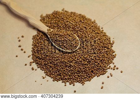 Buckwheat Tea In A Wooden Spoon On A Brown Background. Buckwheat Tea Close-up Macro Photography. Sca