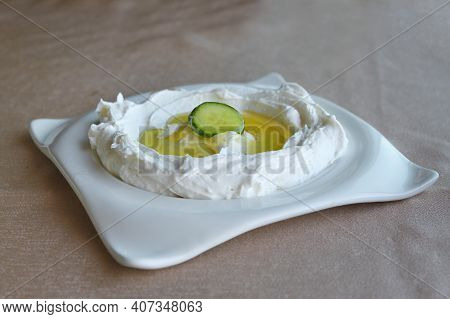 A Fresh Labneh Plate With Olive Oil And A Cucumber.