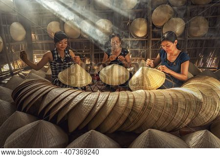 Group Of Vietnamese Female Craftsman Making The Traditional Vietnam Hat In The Old Traditional House