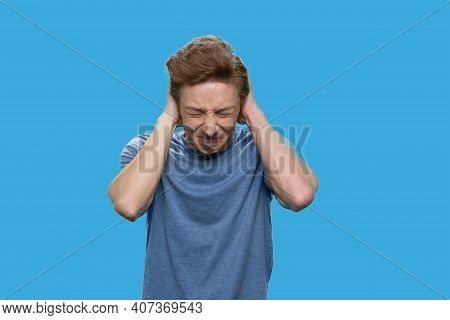 Annoyed Teen Boy Closing His Ears With Hands. American Boy With Clossed Eyes Isolated On Blue Backgr