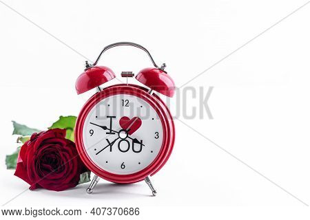 Red Alarm Clock With One Rose On A White Background. Greeting Card For Valentine's Day. Copy Space. 