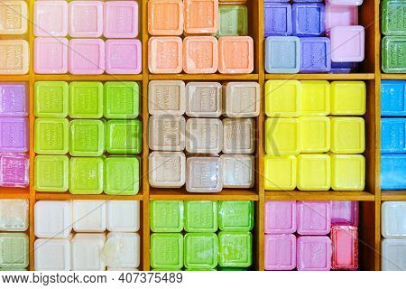 Colorful Pieces Of Soap With Essential Oils And Extracts Stacked On A Wooden Shelf. French Translati