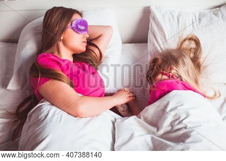Mom And Daughter Sleep Together With Funny Sleep Masks - Stock Image