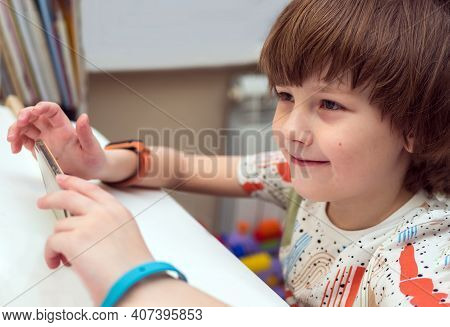 Eight Years Old Caucasian Boy In Casual Wear Is Using Smartphone At Home. Home Education Concept.