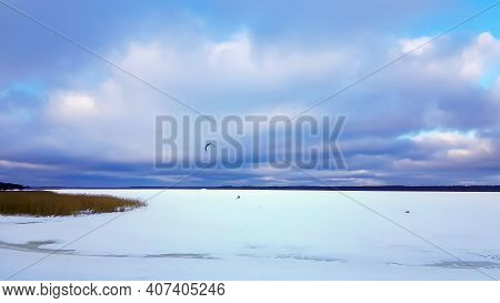 Panorama Of Snowy Lake With Lonely Sportsman Doing Winter Kiting In Riga, Latvia