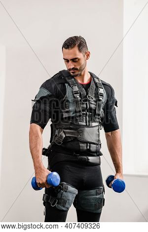 Sporty Man In Electrical Muscular Stimulation Suit Doing Exercise With Dumbbells