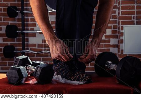 Fitness Motivation And Muscle Training Concept. Man In Sneakers Tying Shoelaces In Sunlight. Athlete