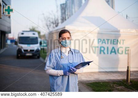 Portrait Of Serious Female Key Front Line Worker In Blue Ppe Uniform,standing Outside Ems Hospital O