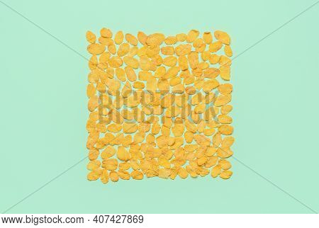 Flat Lay With A Bunch Of Corn Flakes Arranged In A Square On A Green Colored Background. Top View Wi