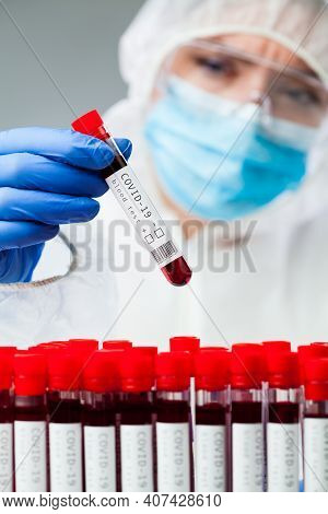 Lab Technician Or Medical Scientist Wearing Protective Suit,face Maks And Goggles, Holding Covid-19 