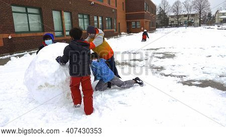 Toronto, Ont., Canada - 12/09/2020: Children With Face Mask Making Snow Ball In The School Backyard 