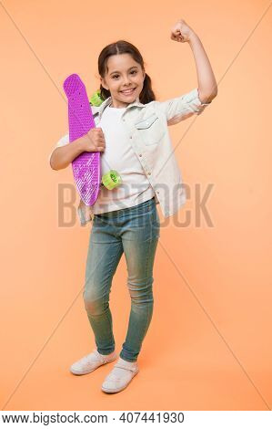 I Can Ride It. Kid Girl Happy Holds Penny Board. Girl Happy Face Carries Penny Board Yellow Backgrou