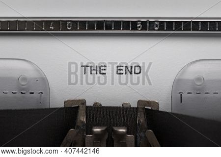 Typing text THE END on vintage manual typewriter. Close up of writes words on white paper. Shot in macro.