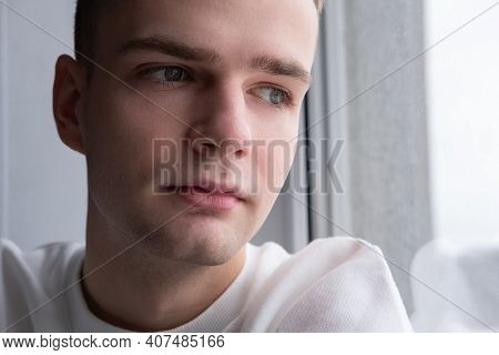 Portrait Of A Sad Pensive Guy At The Window Close-up