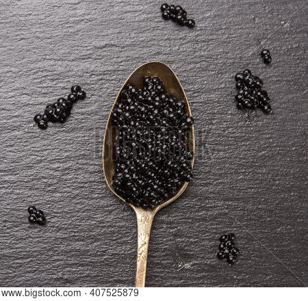 Black Caviar Of Paddlefish Fish In A Spoon, Black Background, Top View