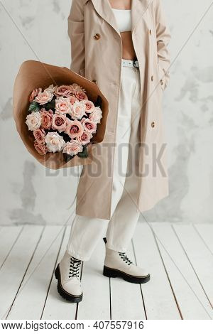 A Beautiful Woman Holds A Bouquet Against A Wall Background. A Bouquet Of Roses.