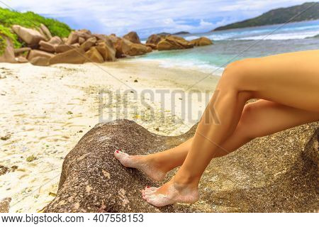 Sexy Tanned Bare Legs Laying On The White Sand Beach Of Seychelles Islands. Woman With Red Polished 
