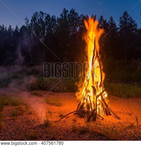Landscape Of Forest At White Night. Close-up Of Huge Fire. Traditional Midsummer Ligo Celebration.