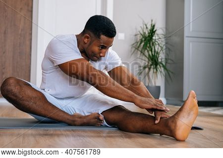 Portrait Of Flexible African-american Man Practicing Yoga Sitting In Janu Sirsasana Exercise, Head T