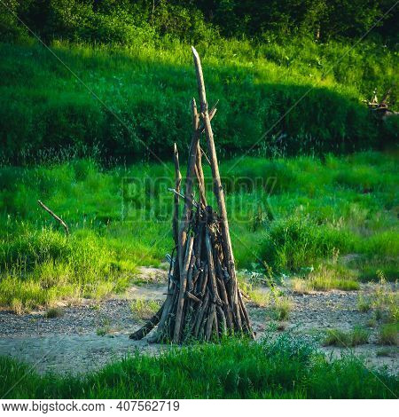 Close-up Of Woodpile Of Dry Branches For A Huge Fire. Midsummer Celebration Preparation. Green Grass