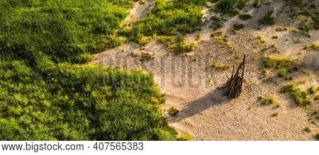 Midsummer Celebration Preparation. Drone View Of Woodpile Of Dry Branches On The Sand. Green Grass.