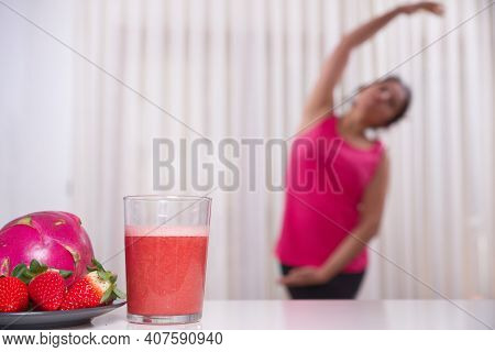 Green Smoothie With Focused Kiwis And Woman Exercising On Unfocused Background