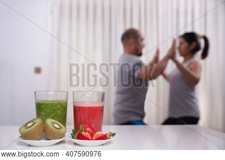 Green Smoothie With Focused Kiwis And Woman Exercising On Unfocused Background