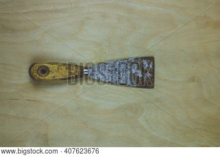Old Dirty And Rusty Putty Knife Or Spatula Isolated On Wooden Background. High Quality Photo