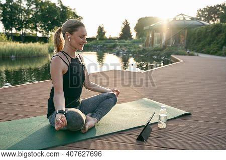 Change Your Life. Beautiful Middle Aged Woman Sitting In Lotus Pose And Smiling While Doing Yoga On 