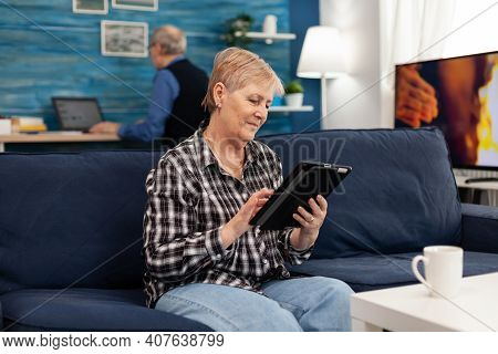 Smiling Senior Woman With Tablet Pc Resting On Sofa Elderly Woman Using Moder Technoloy Tablet Pc In
